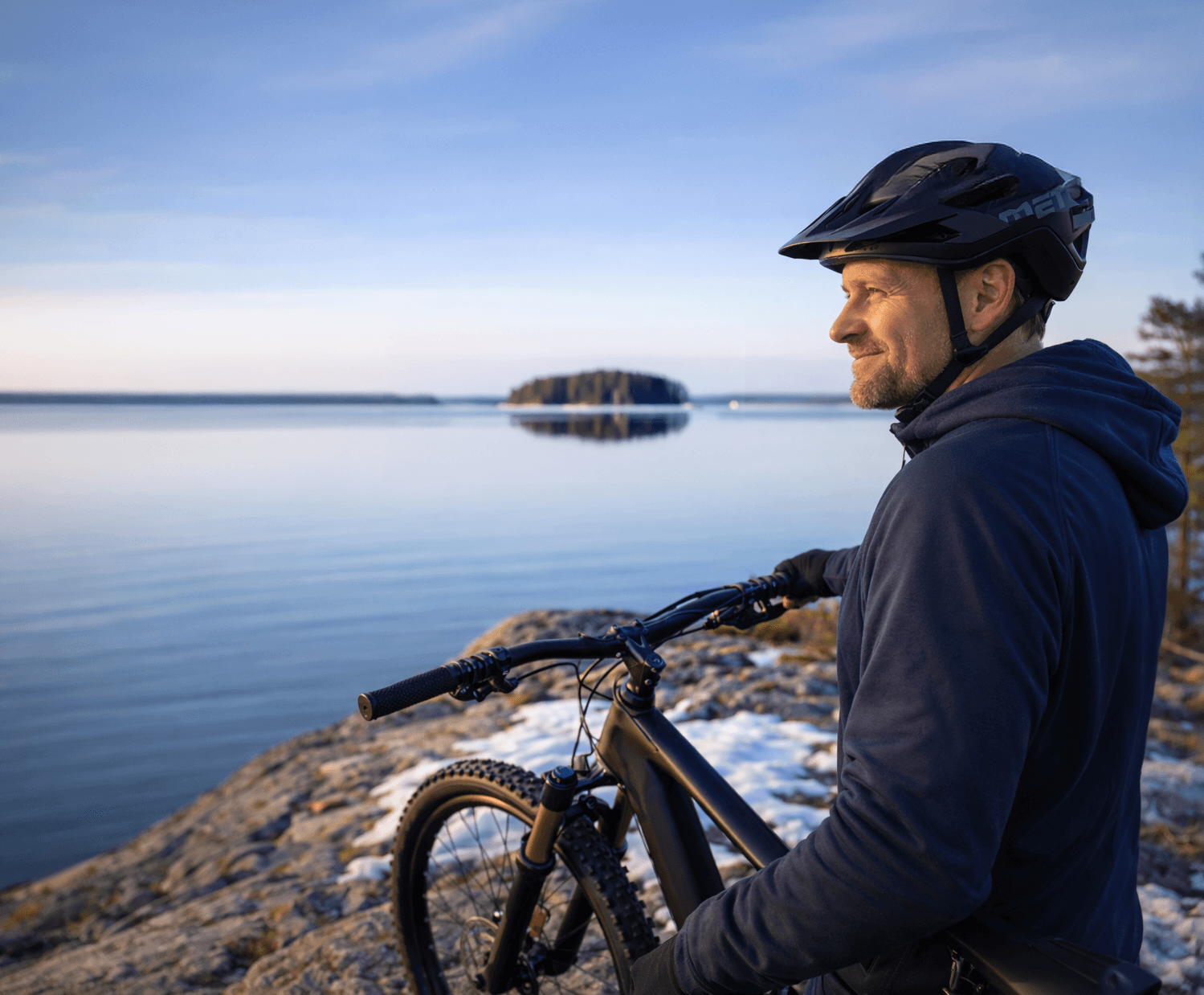 Mies pyörän kanssa järven rannalla